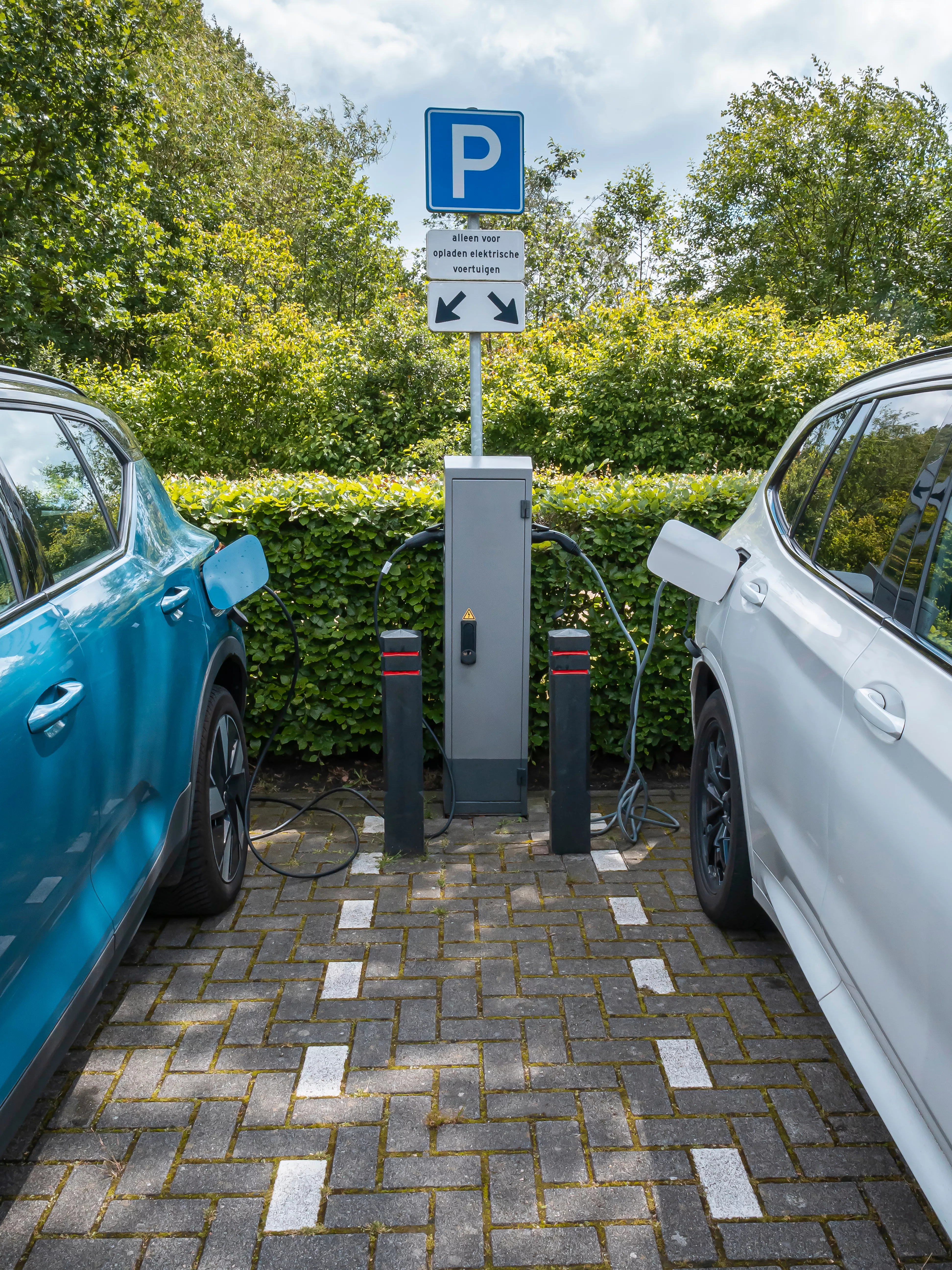 Power supply plugged into electric cars being charged on public charging station