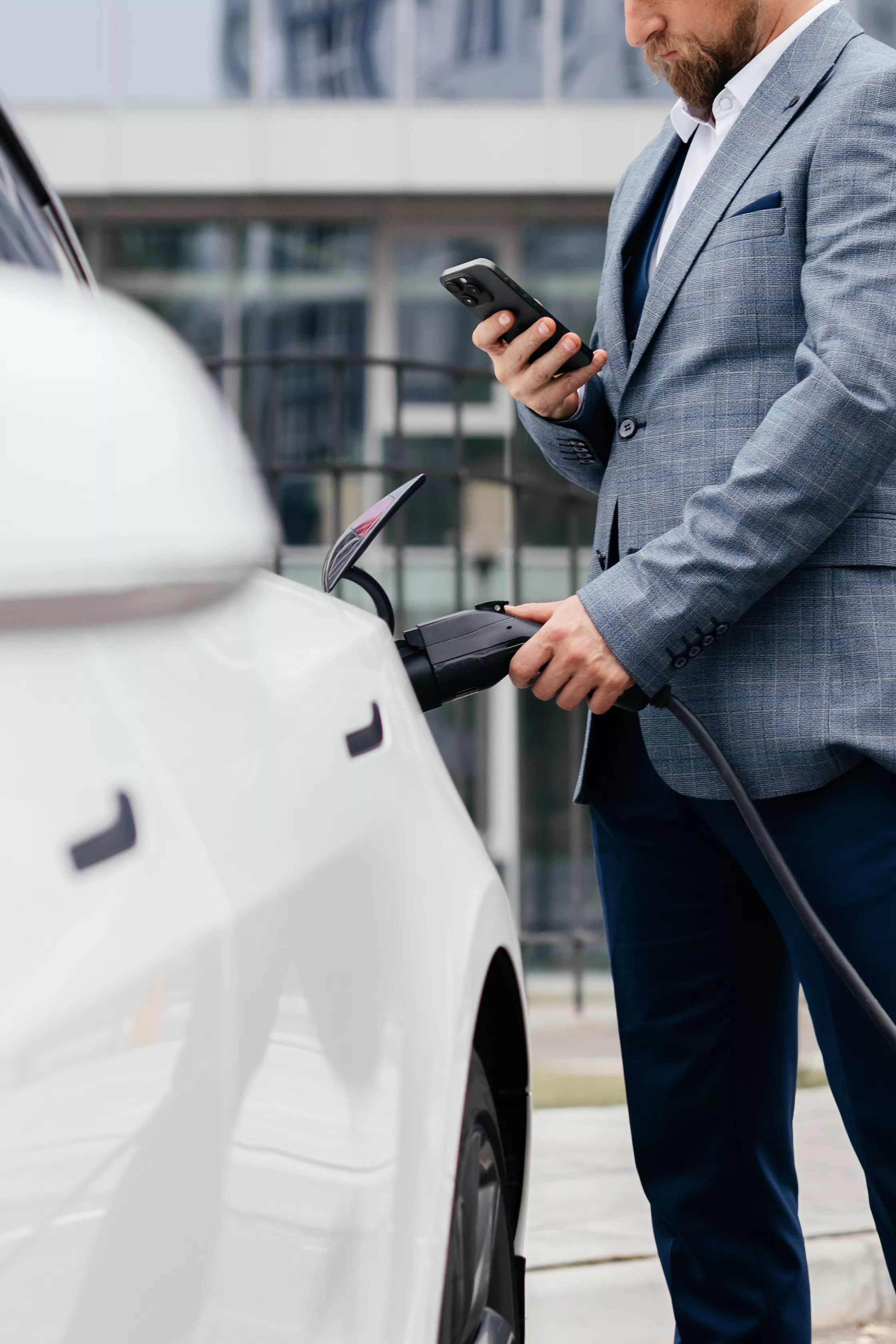 Businessman plugging electric car from charging station. Senior is plugging in power cord to an electric car