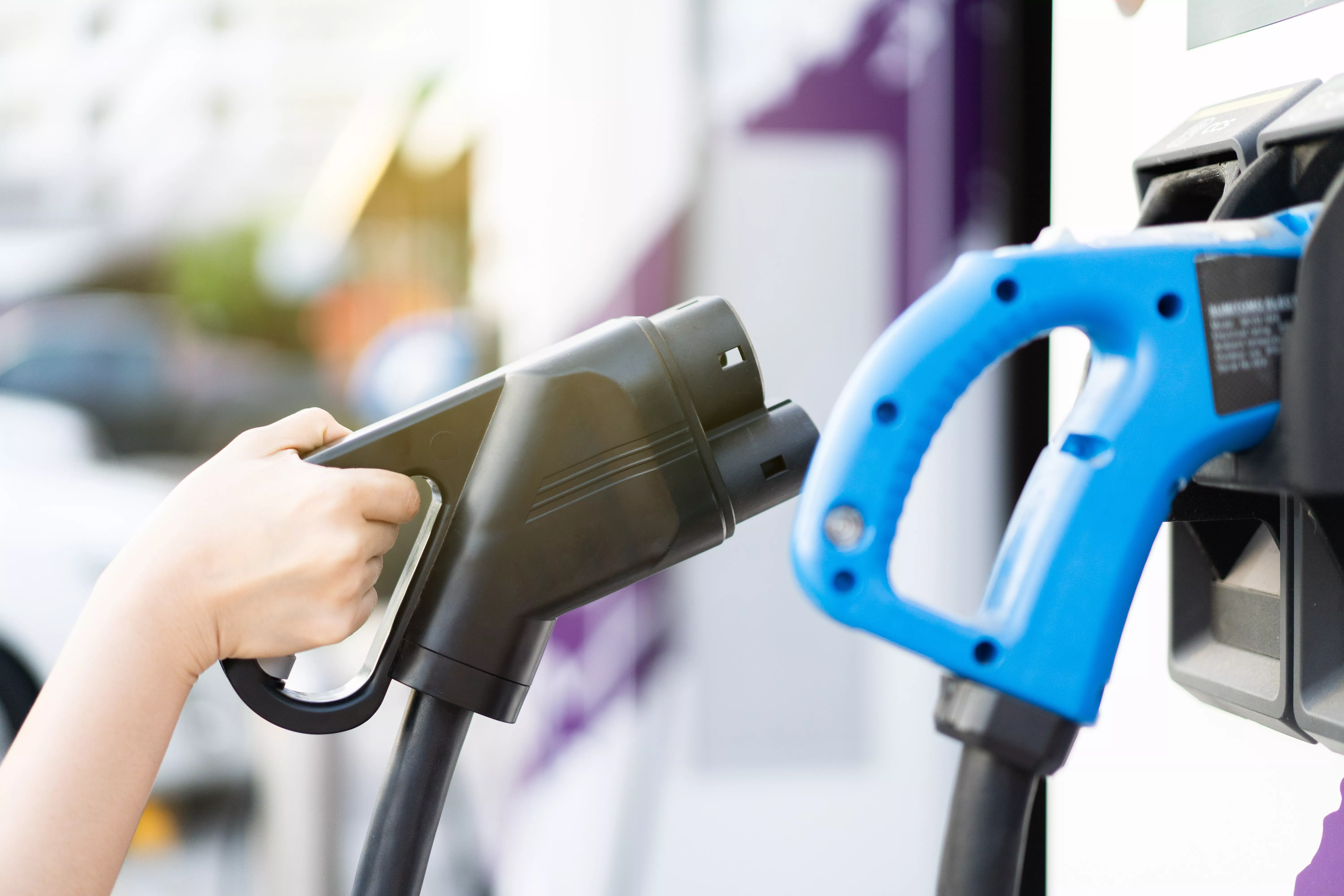 woman holding aa DC - CCS type 2 EV charging connector at EV charging station